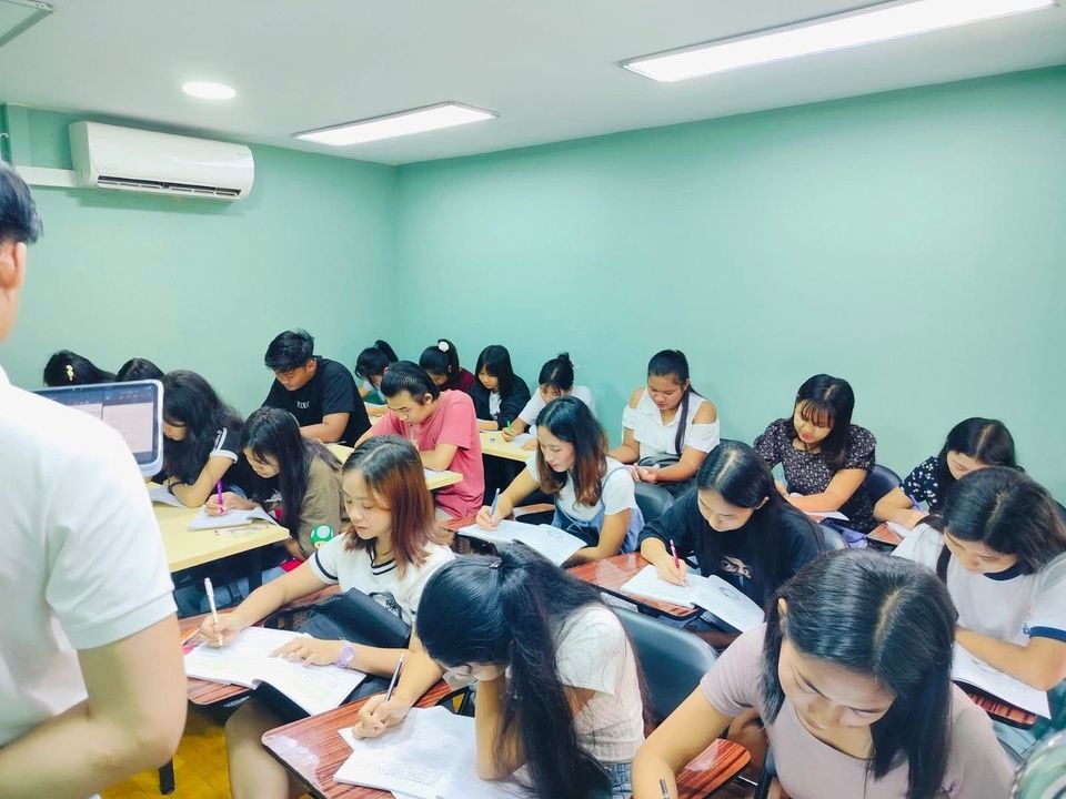 教室で日本語の筆記練習をする学生たち